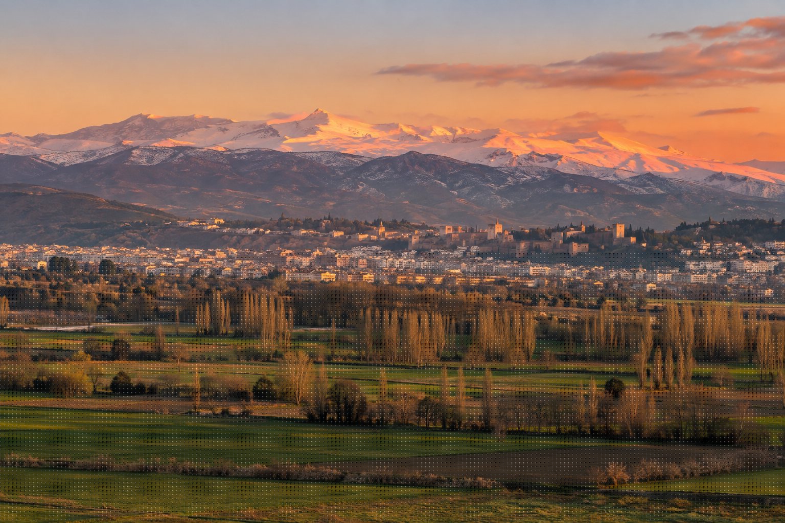 Panorámica al atardecer desde Las Gabias con la Vega en primer plano, Granada al centro y Sierra Nevada nevada al fondo teñida de rosa (imagen ilustrativa)